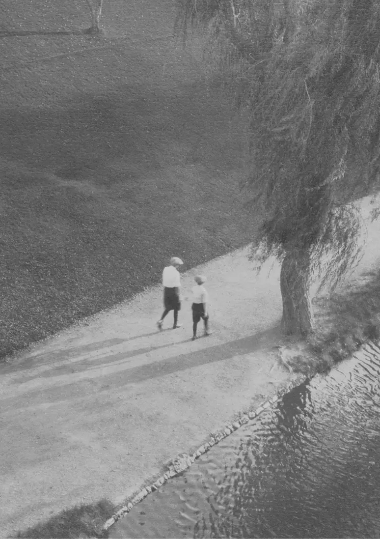 Foto en blanc i negre centrada en una dona i un nen de lluny.